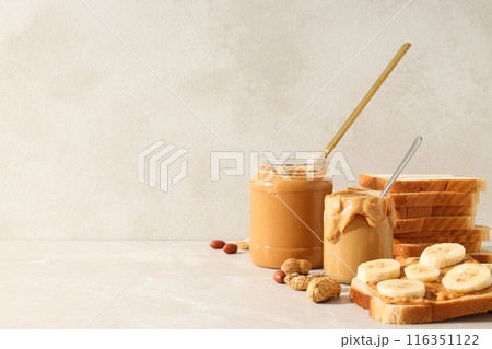 Peanut paste in a glass jar, on a light background. Peanut paste in a glass jar, on a light background. 116351122