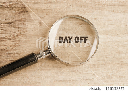 Business and Day off concept. Day off symbol. Concept word Day off through a magnifying glass on papyrus 116352271