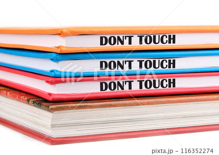Words DO NOT TOUCH written on the ends of notebooks lying on top of each other on a white background Words DO NOT TOUCH written on the ends of notebooks lying on top of each other on a white background 116352274