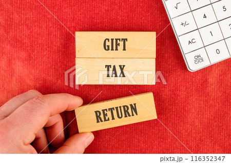 Text GIFT TAX RETURN on wooden blocks with a hand, part of a calculator on a red background Text GIFT TAX RETURN on wooden blocks with a hand, part of a calculator on a red background 116352347