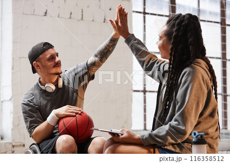 Portrait of tattooed man with disability high five with young woman while playing basketball together Portrait of tattooed man with disability high five with young woman while playing basketball together 116358512