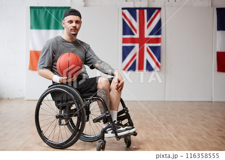 Full length portrait of young man with disability using wheelchair and looking at camera while playing adaptive basketball in indoor court copy space Full length portrait of young man with disability using wheelchair and looking at camera while playing adaptive basketball in indoor court copy space 116358555