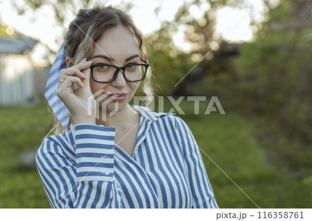 Optics for vision and fashion. A sexy girl looks at the camera on her glasses . Beautiful look through the frames close-up Optics for vision and fashion. A sexy girl looks at the camera on her glasses . Beautiful look through the frames close-up 116358761