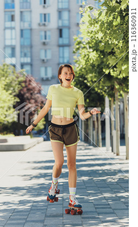 Cheerful skater girl, teenager, enjoying sunny day in city, wearing bright athletic wear and cruising on retro roller skates. 116360911