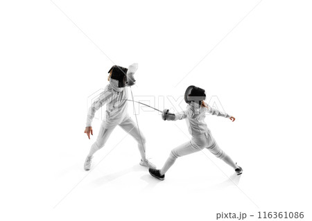 In fencing training session, two female competitors work on their attack and parry sequences against white studio background. 116361086