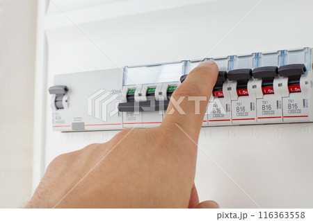 Hand Adjusting Circuit Breakers on Panel 116363558