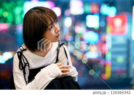 夜に光輝く繁華街と若い女性 116364342