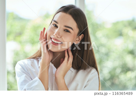 Smiling Woman Holding Face With Hands In Natural Light Smiling Woman Holding Face With Hands In Natural Light 116365489