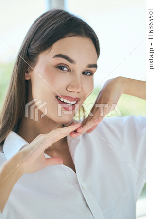 Smiling Woman Posing with Hands Framed Around Her Face Indoors Smiling Woman Posing with Hands Framed Around Her Face Indoors 116365501