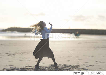 A woman is dancing on the beach in a black skirt 116365852