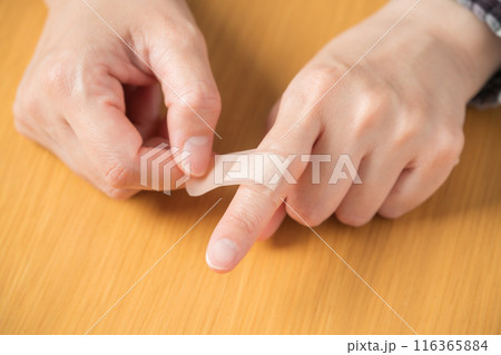 指に絆創膏を貼る人の手元 指に絆創膏を貼る人の手元 116365884