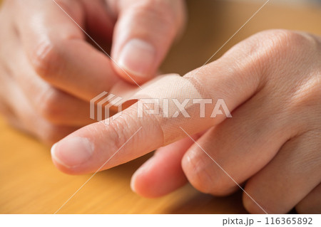 指に絆創膏を貼る人の手元 116365892