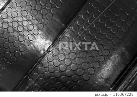 Rubber mat with a non-slip pattern covers an industrial stairway 116367229