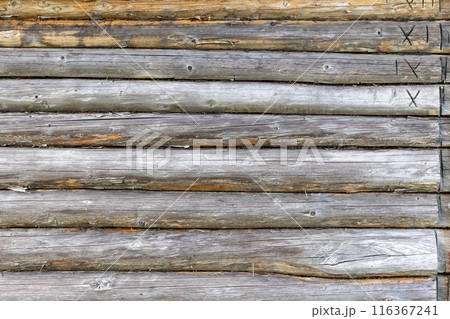 Old wooden wall made of gray pine tree logs with roman numerals Old wooden wall made of gray pine tree logs with roman numerals 116367241