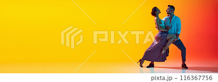 Bachata dance class. Couple, man and woman in dynamic pose highlighting passion of bachata dance against gradient yellow orange background in neon light 116367756