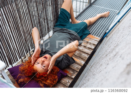 portrait red-haired curly young woman enjoying relaxation on balcony or terrace portrait red-haired curly young woman enjoying relaxation on balcony or terrace 116368092