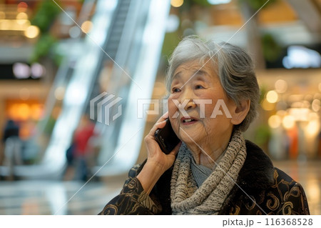 An elderly asian pensioner grandmother speaks on the phone in a shopping center. New communication technologies 116368528