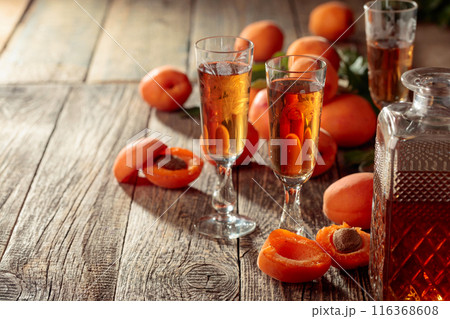 Apricot liquor and fresh apricots on a old wooden table. 116368608