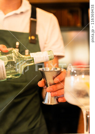 Hands of a bartender measuring the dose of alcohol before preparing the drink. Vertical 116369438
