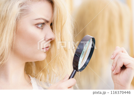 Woman magnifying her split ends hair Woman magnifying her split ends hair 116370446