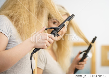 Woman using hair curler 116370469