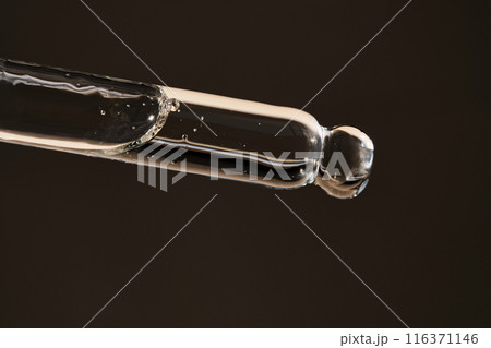 Pipette with serum on a dark beige background. Pipette with serum on a dark beige background. 116371146