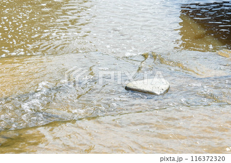 Water flows around a stone with a smooth surface. Water flows around a stone with a smooth surface. 116372320