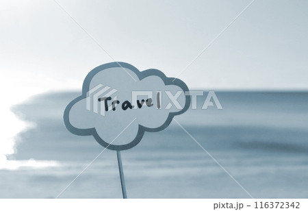 Stick with paper speech bubble with words Travel on background blue sea, sky, sandy beach on sunny summer day. Text-balloons with text from letters. Concept, symbol, sign vacation travel. Blue color 116372342