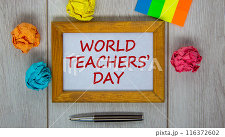 Wooden frame with inscription 'World Teachers' Day' on beautiful wooden table, colored paper, metalic pen. Concept. 116372602