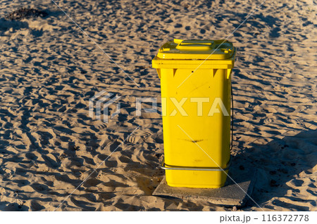 Yellow trash can on a sandy beach 116372778