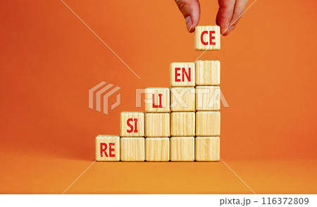 Resilience symbol. Concept word Resilience on beautiful wooden cubes. Beautiful orange background. Businessman hand. Business resilience concept. Copy space. Resilience symbol. Concept word Resilience on beautiful wooden cubes. Beautiful orange background. Businessman hand. Business resilience concept. Copy space. 116372809