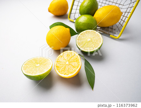 Fresh lemons and limes fall out of  a supermarket basket on a blue background. Citrus fruit concept 116373962