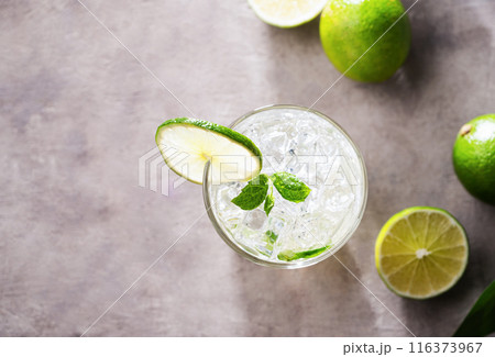 Refreshing mojito cocktail with mint and lime in a glass with ice on pink background with shadows 116373967