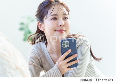 リビングでスマートフォンを使う女性 リビングでスマートフォンを使う女性 116376484