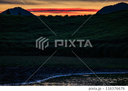 2024年夏曽爾高原の夕景　三脚固定　お亀池の対岸の丘へ沈んで行く夕日と夕焼け　山の間の茜雲② 116376676