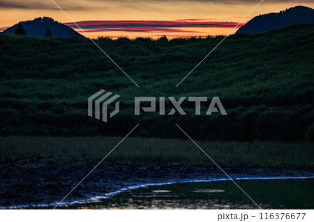 2024年夏曽爾高原の夕景　三脚固定　お亀池の対岸の丘へ沈んで行く夕日と夕焼け　山の間の茜雲③ 116376677