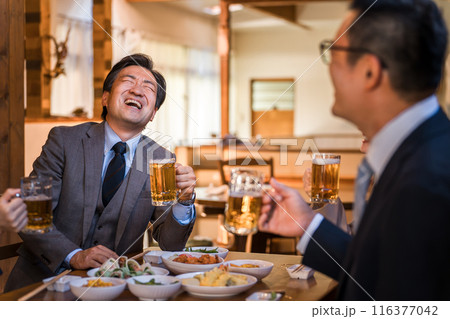 居酒屋で忘年会・新年会・飲み会・宴会で爆笑する中年のビジネスマン男性 116377042