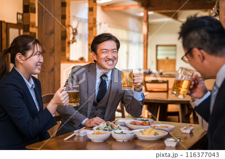 居酒屋で忘年会・新年会・飲み会・宴会をする仕事仲間・同僚・上司部下の男女 116377043