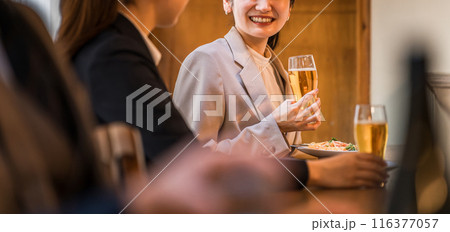 居酒屋・飲み屋のカウンターで部下と楽しくお酒を飲むビジネスウーマン 116377057