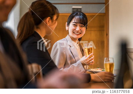 居酒屋・飲み屋のカウンターで部下と楽しくお酒を飲むビジネスウーマン 116377058