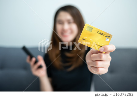 Asian woman showing her credit card for shopping online on mobile phone applications. Asian woman showing her credit card for shopping online on mobile phone applications. 116378282