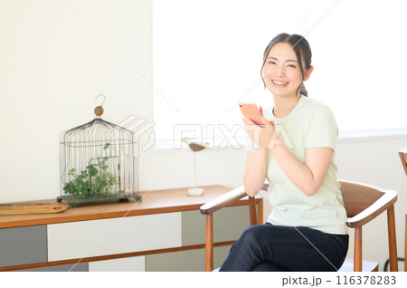 椅子に座ってスマホを操作する女性 116378283