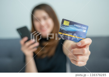 Asian woman showing her credit card for shopping online on mobile phone applications. Asian woman showing her credit card for shopping online on mobile phone applications. 116378285