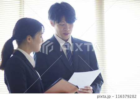 オフィスで書類を読み合わせる男女の会社員 オフィスで書類を読み合わせる男女の会社員 116379282