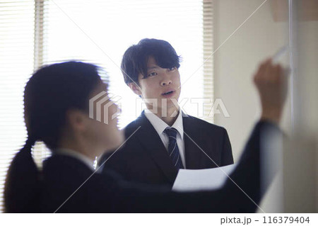 会議で提案内容を説明する男性会社員と女性同僚 116379404
