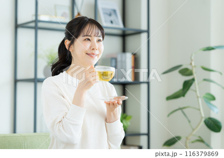 リビングでハーブティを飲む若い女性 116379869