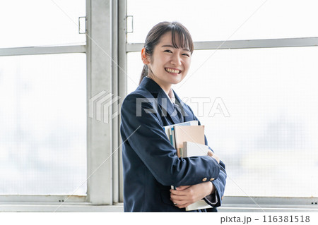 教室で教科書を持つ制服姿の女子高生 116381518