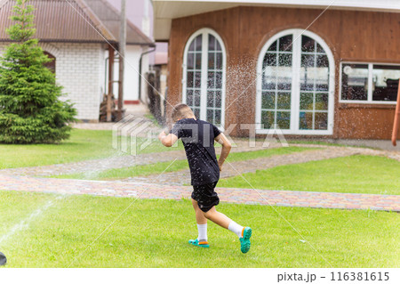 Young white boy running under the water from the sprinkler Young white boy running under the water from the sprinkler 116381615