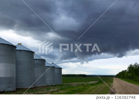 Stormy sky over old granaries along the country road. Stormy sky over old granaries along the country road. 116382748