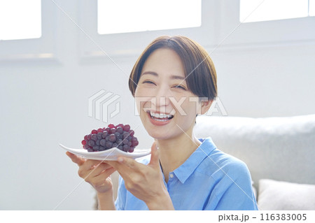 自宅でぶどうを食べる女性 カメラ目線 自宅でぶどうを食べる女性 カメラ目線 116383005